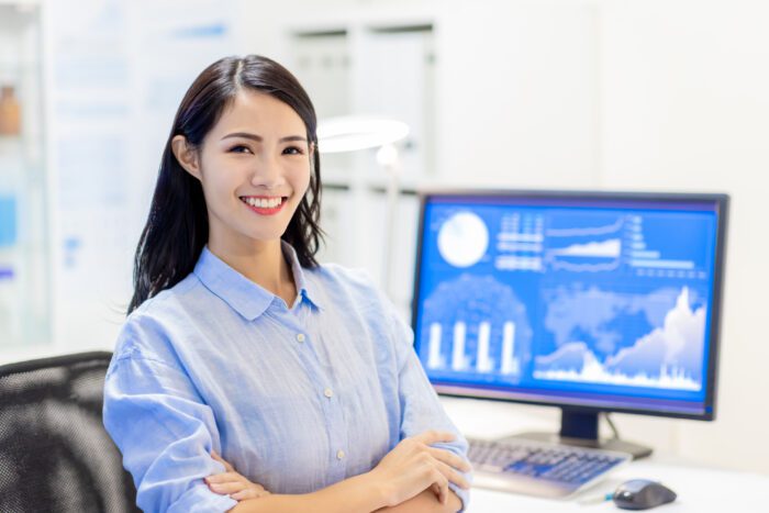 Asian female office worker smile at you with cross arm in office