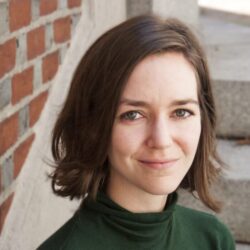 An image of a woman standing in front of a brick wall