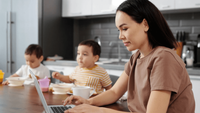 Women working on laptop with children in the background