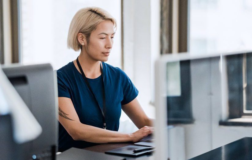 Woman sits in front of a desktop computer