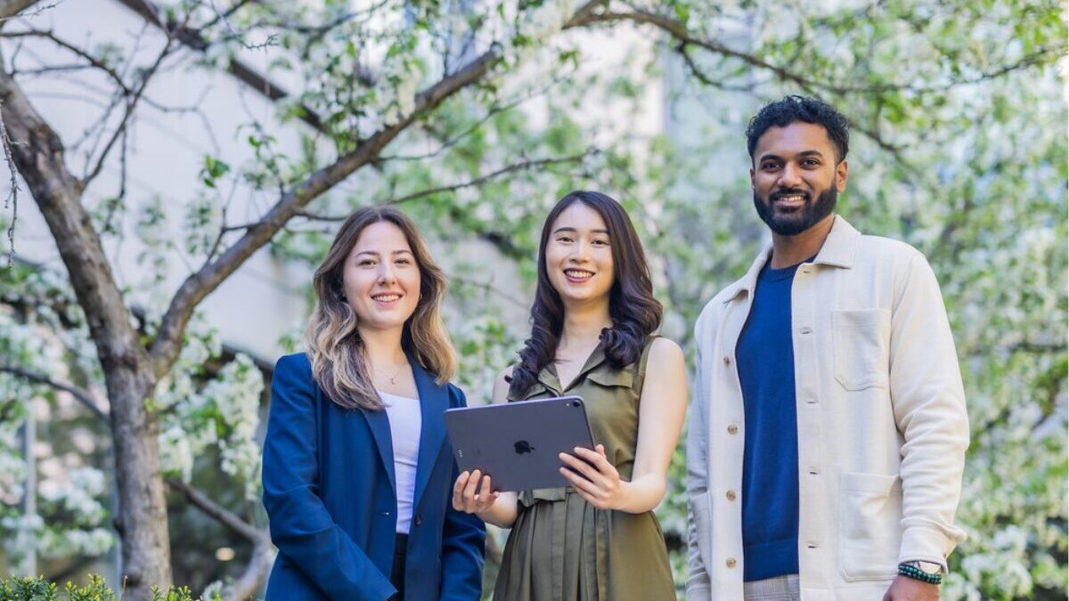 Three person standing in font of Schulich Building