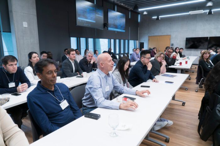 Image showing Schulich faculty members, seated at tables, listening to a discussion